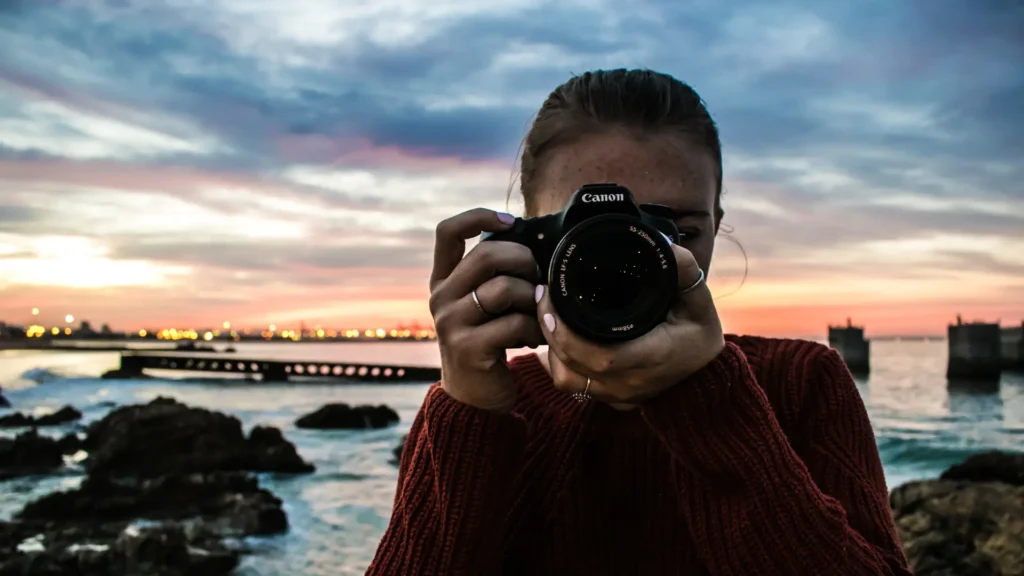 Lady taking a picture using a Canon camera. Decorative image for Canon STM vs USM lenses article.